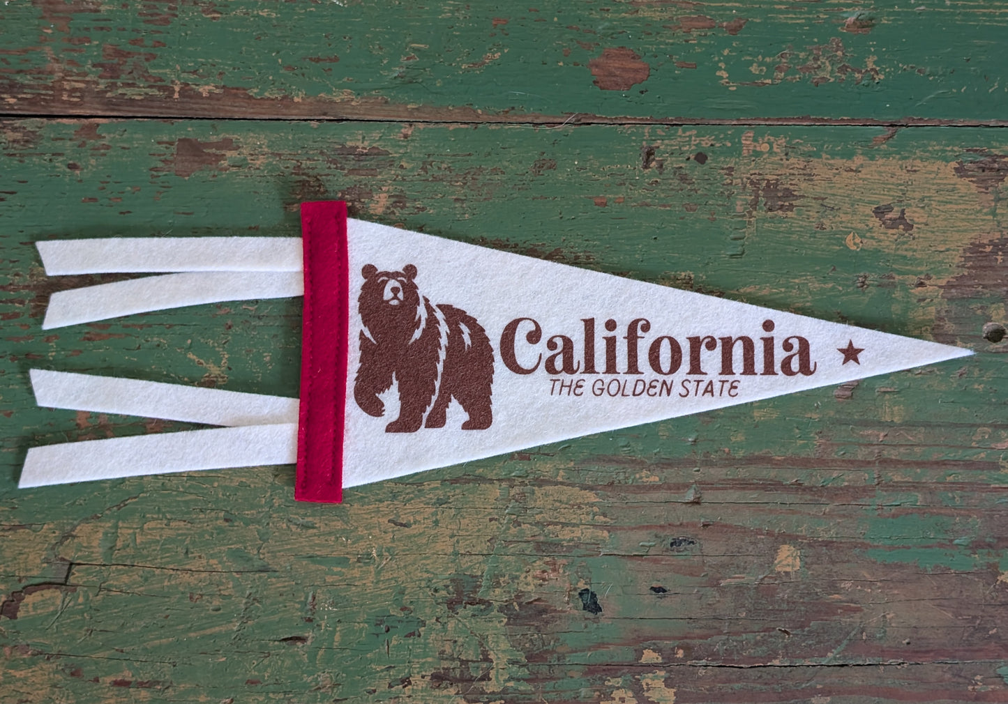 Mini soft white pennant with the words "California: The Golden State", a red border, and a bear in brown ink.