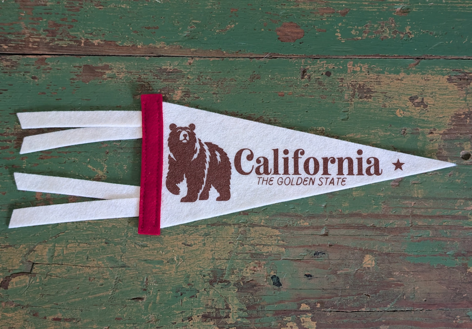 Mini soft white pennant with the words "California: The Golden State", a red border, and a bear in brown ink.