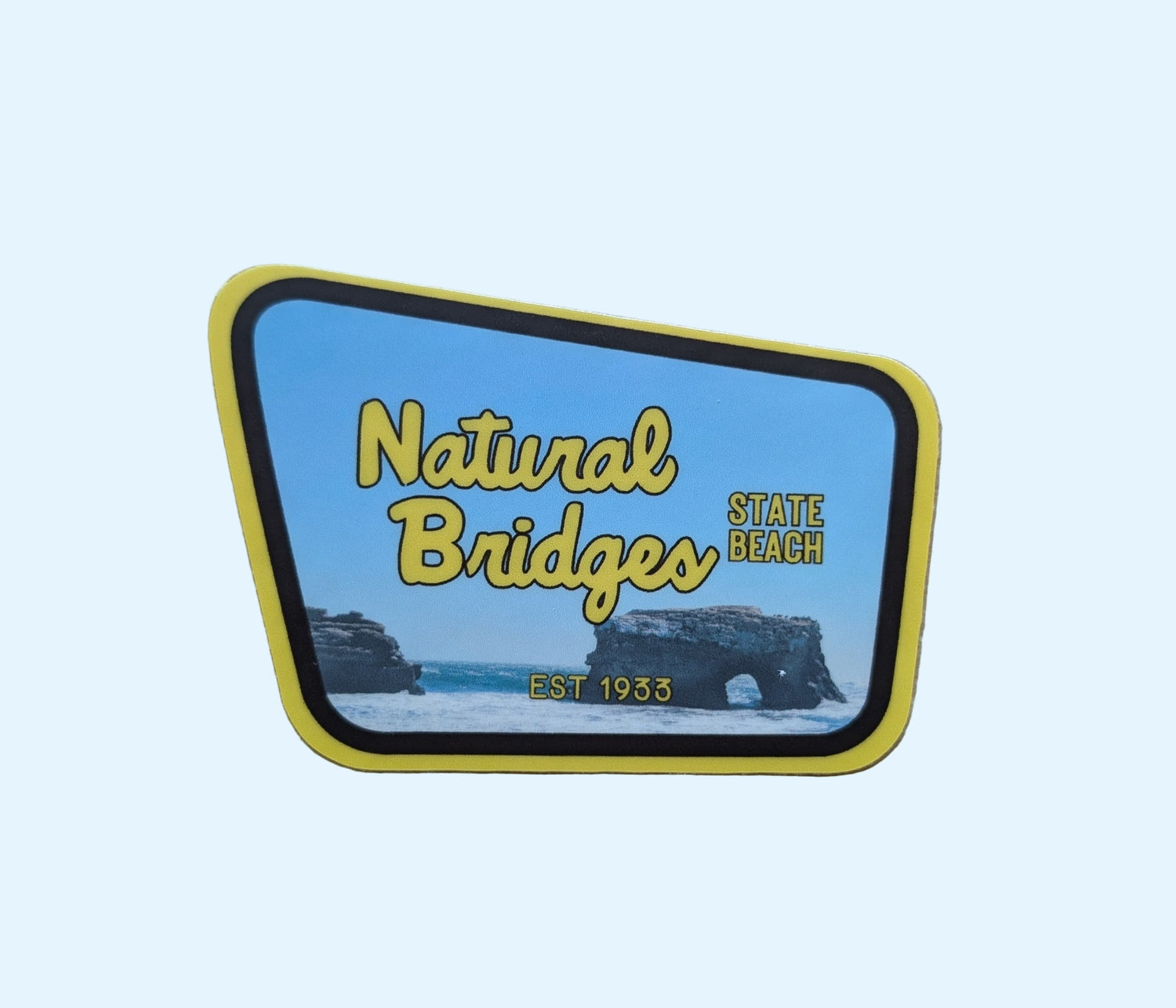 yellow + brown bordered sticker represents Natural Bridges State Beach with paper background