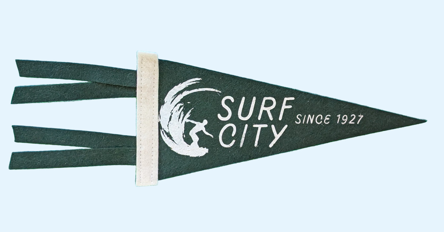 Surf City, Since 1927 souvenir pennant representing Santa Cruz California with a surfer in a wave on dark green felt