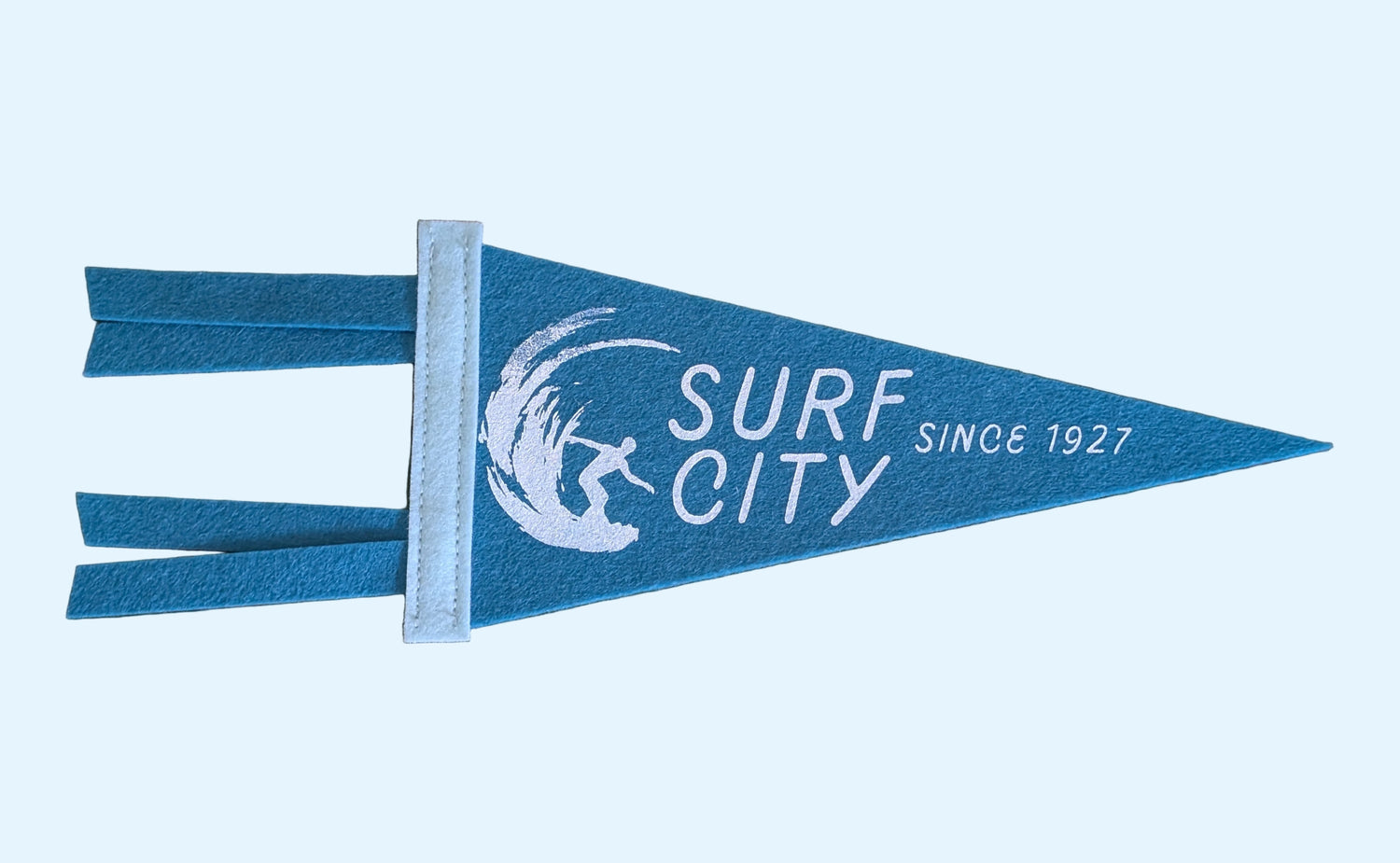 Mini blue pennant with the words "Surf City: Since 1927" as an homage to Santa Cruz, California with a mist blue border and a surfer in white ink