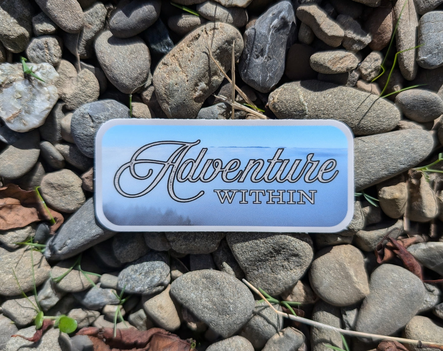 gray bordered sticker represents exploring inwards to build our inner sanctuary reading: Adventure Within