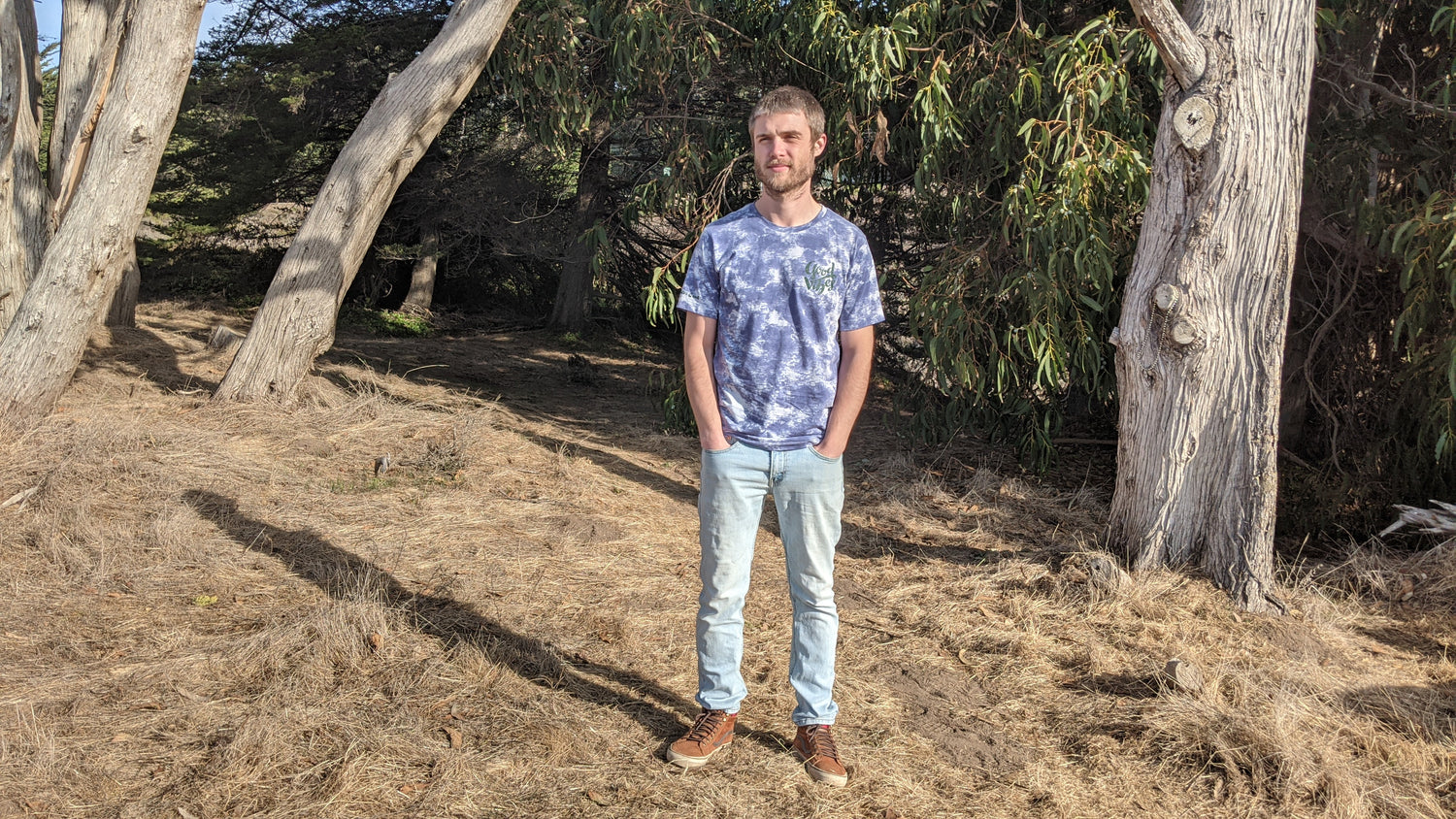 Model wearing blue and white tie dye Good Vibes shirt with jeans