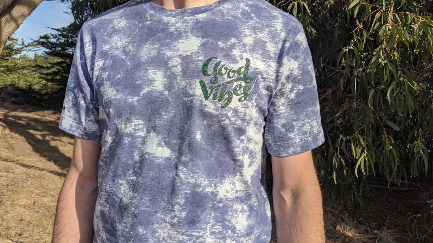 Blue and white tie dye shirt with Good Vibes in green ink on the front