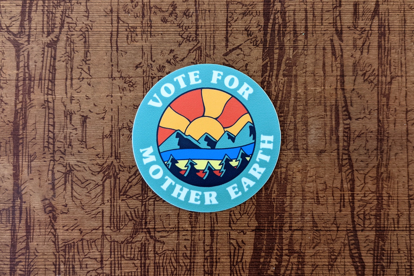 Round sticker that reads Vote for Mother Earth with Mountainscape sunset scene