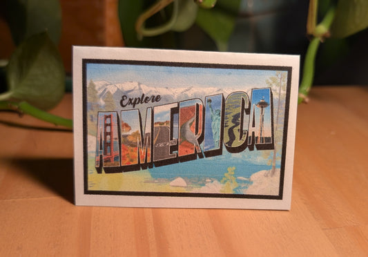 Mini card with America vintage letter art design on confetti white paper standing up on desk with plant in background
