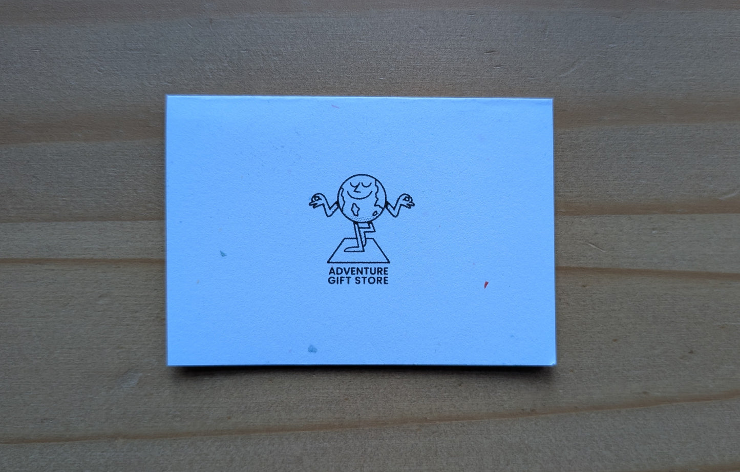 Mini card back with adventure gift store logo on confetti white paper