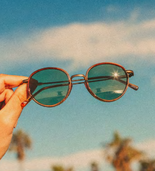 Baia sunglasses by Sunski held up against the sky