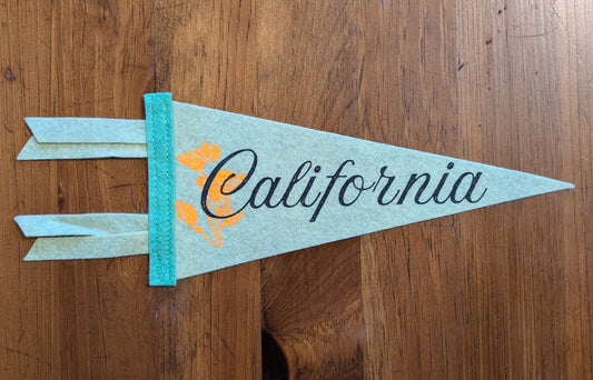 Mini pistachio pennant with the words "California" in black and a bright orange poppy