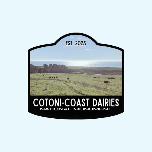 Black-bordered sticker  that reads Cotoni-Coast Dairies National Monument, Est 2025, with a photo of this new local gem north of Santa Cruz, California, USA in the background