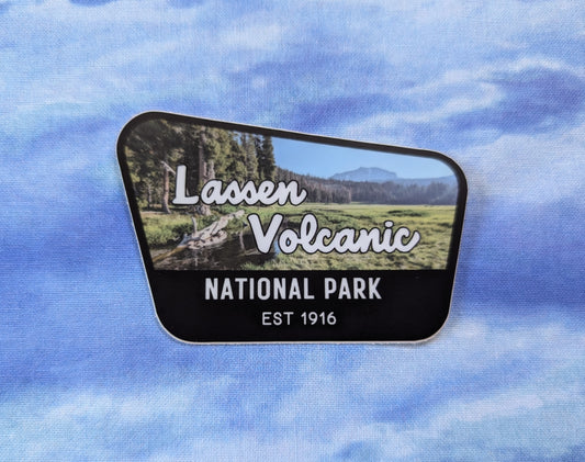 Lassen Volcanic National Park badge sticker with black border and photo of meadow and Lassen Peak volcano in the background