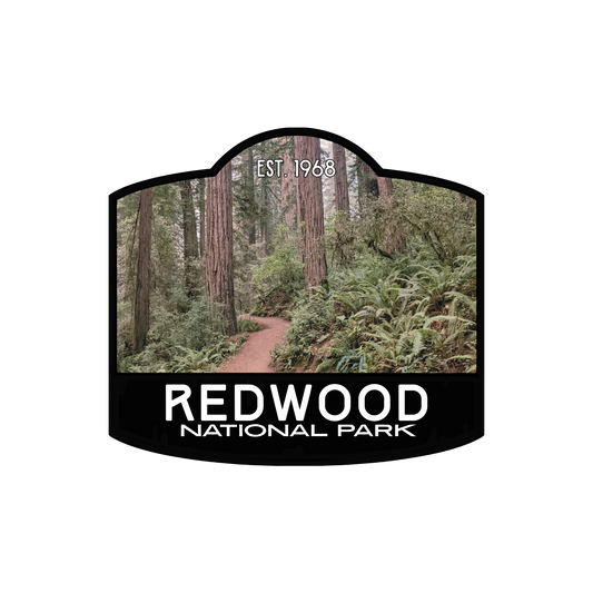 Redwood National Park badge sticker with black border and photo of old growth redwood trail in background