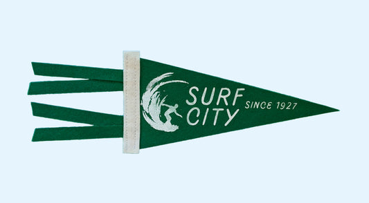 Surf City, Since 1927 souvenir pennant representing Santa Cruz California with a surfer in a wave on forest green felt