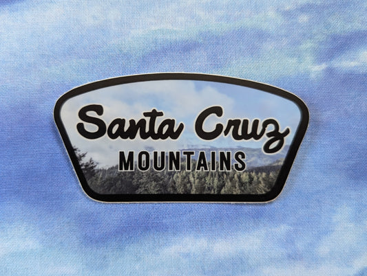 Santa Cruz Mountains badge sticker with black border and photo of foggy mountainside as background