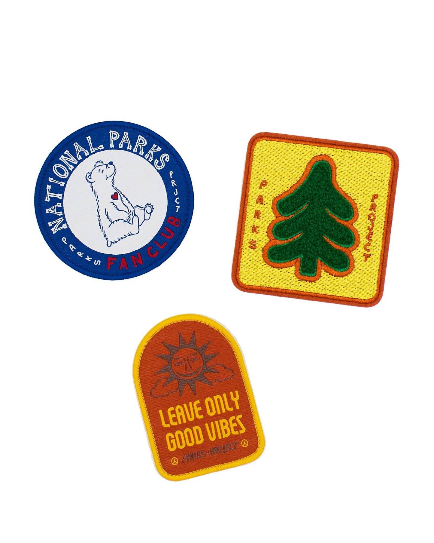Patch collection by Parks Project with round National Parks bear fan club patch, pine tree chenille patch and Leave Only Good Vibes sunshine orange patch