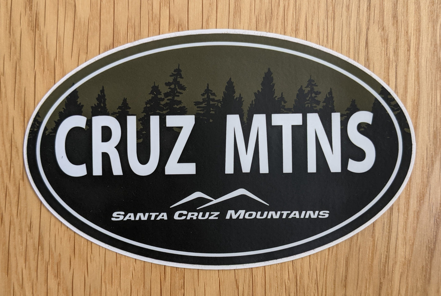 Oval Cruz Mtns sticker with forest silhouette, by SCM Clothing