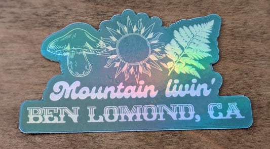 Mountain Talk holographic green sticker reading Mountain Livin' Ben Lomond, CA with sun, fern and mushroom design