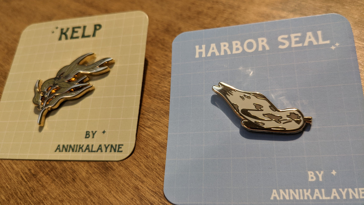 Harbor Seal and Kelp enamel pins by Annika Layne