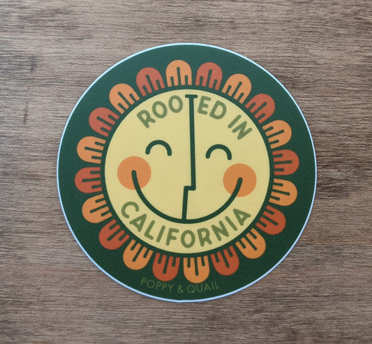 Round sticker with smiley flower reading" Rooted in California" by Poppy & Quail